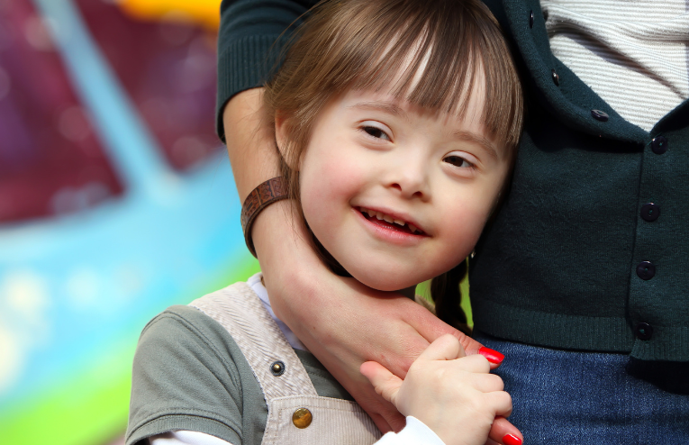 Child with a disability is holding mothers hand and smiling.